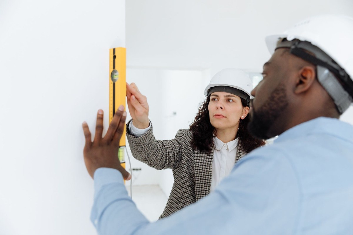 Professionnels en casques vérifient l'alignement d'un niveau sur un mur