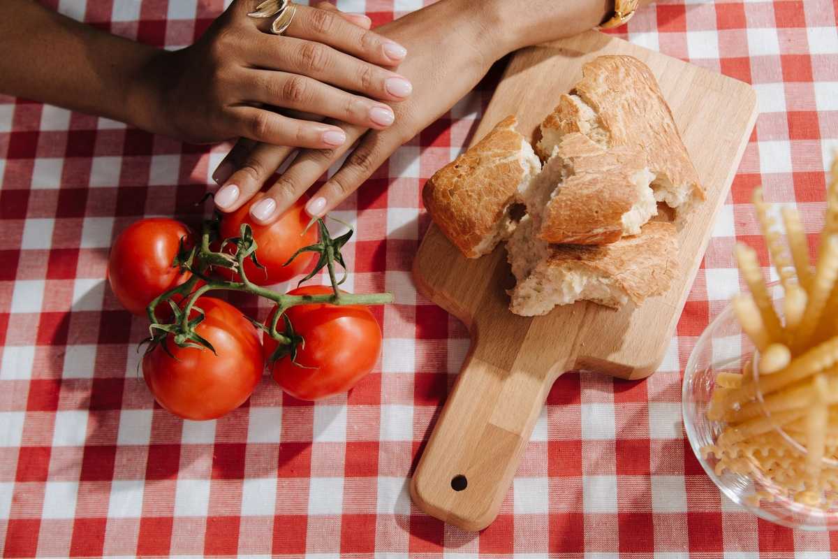 Mains, tomates, pain, frites sur table à carreaux