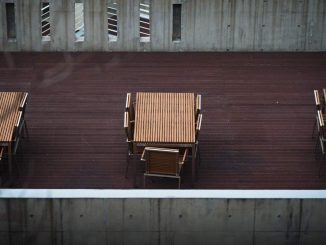 Des tables en bois et chaises sur une terrasse de béton