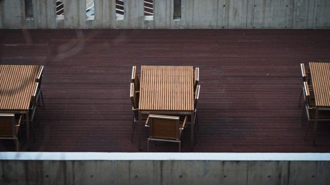 Des tables en bois et chaises sur une terrasse de béton