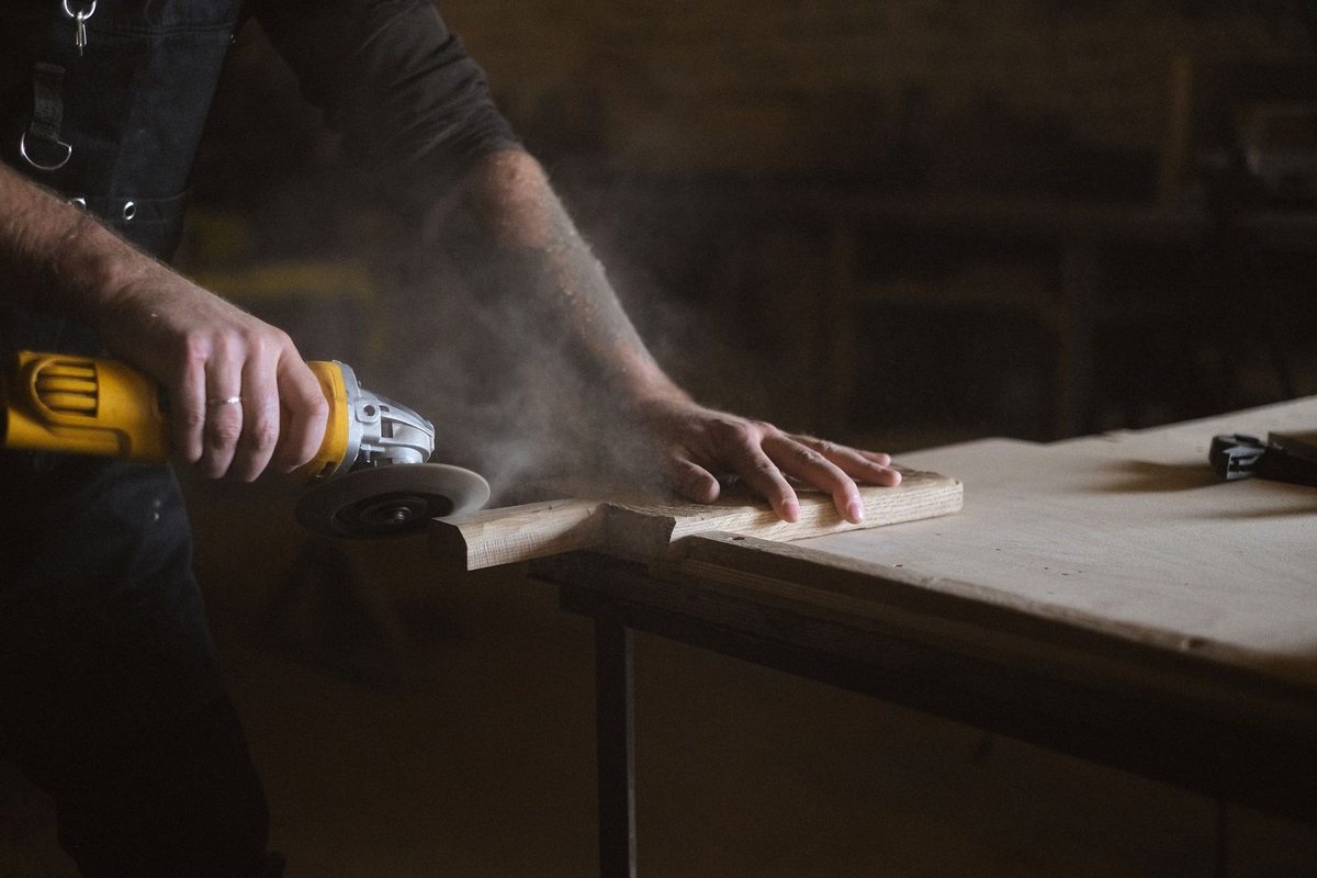 Personne utilisant une lime électrique sur une planche en bois dans un atelier