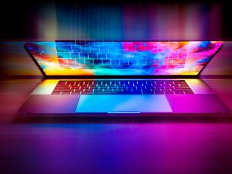 Un ordinateur portable ouvert projette des couleurs vives sur le bureau