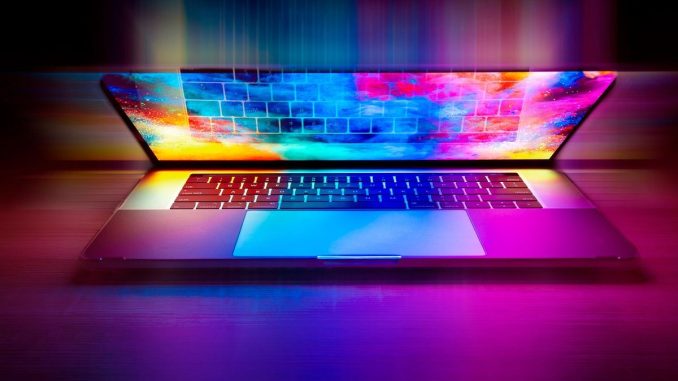 Un ordinateur portable ouvert projette des couleurs vives sur le bureau