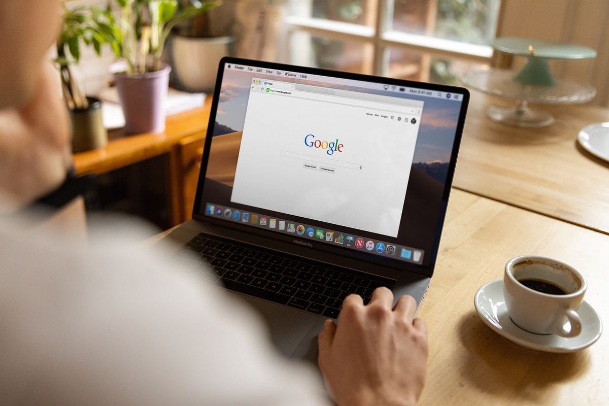 Personne utilise ordinateur portable avec Google, tasse de café à côté Personne utilise ordinateur portable avec Google, tasse de café à côté