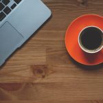 Un ordinateur portable et une tasse de café sur une assiette orange