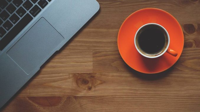Un ordinateur portable et une tasse de café sur une assiette orange