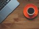 Un ordinateur portable et une tasse de café sur une assiette orange